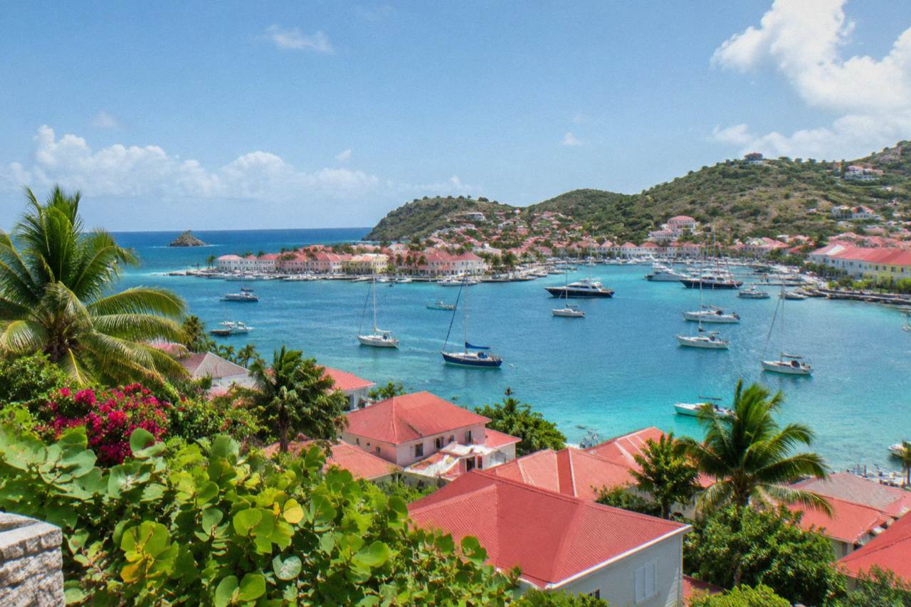 A hillside view over red rooftops and a turquoise Caribbean bay on St Barts