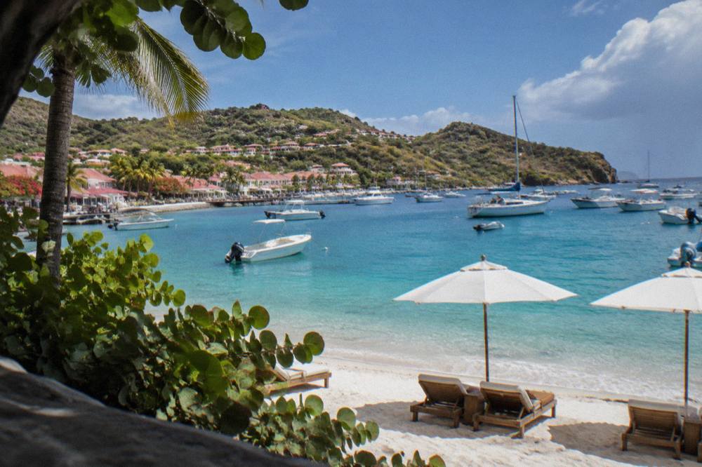 Sun loungers and umbrellas on a white sand beach beside calm turquoise water