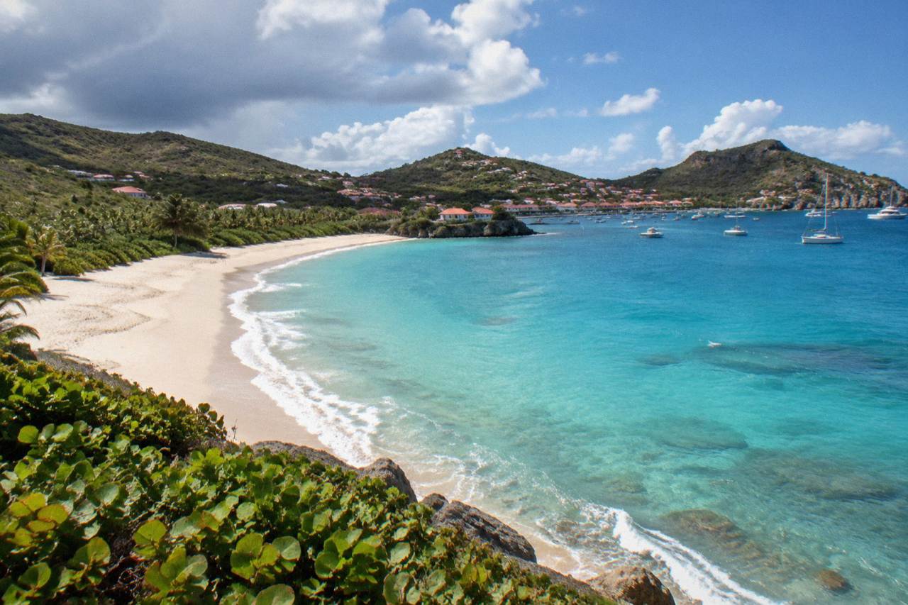 A curved sandy beach below green hills on a small Caribbean island