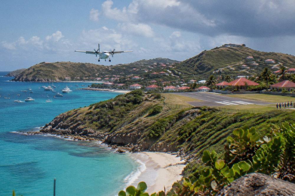 Turboprop aircraft on the short runway at Gustaf III Airport in St Barts with hills behind