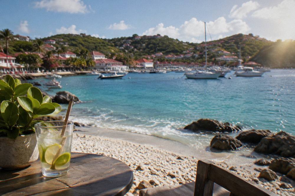 Turquoise water breaking on a shell-covered shoreline with rocky points on either side near Gustavia