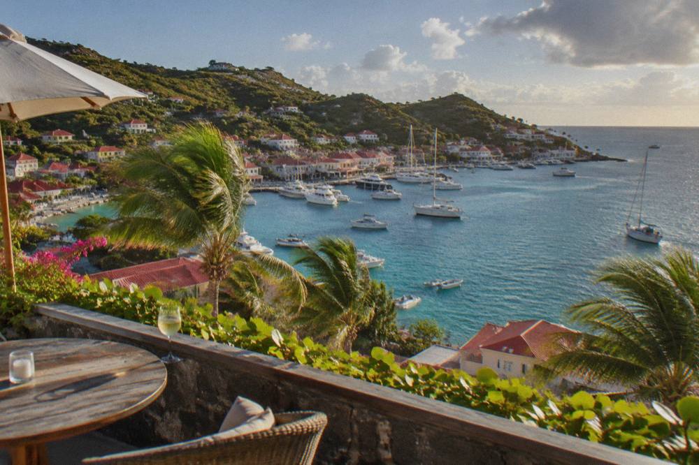 An open terrace above the sea at dusk with a breeze moving the palm trees