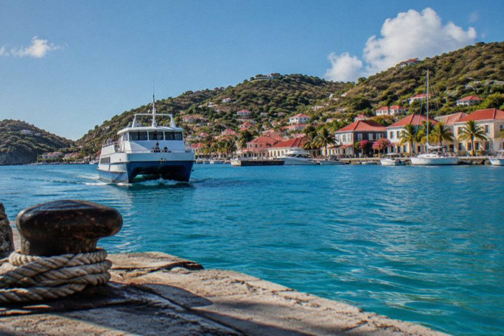 A passenger ferry approaching the harbor front of Gustavia in St Barts under a clear sky