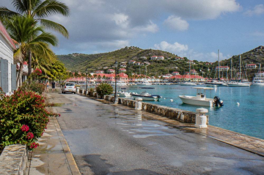 Wooden signpost pointing toward beaches and villages on a hillside road on St Barts