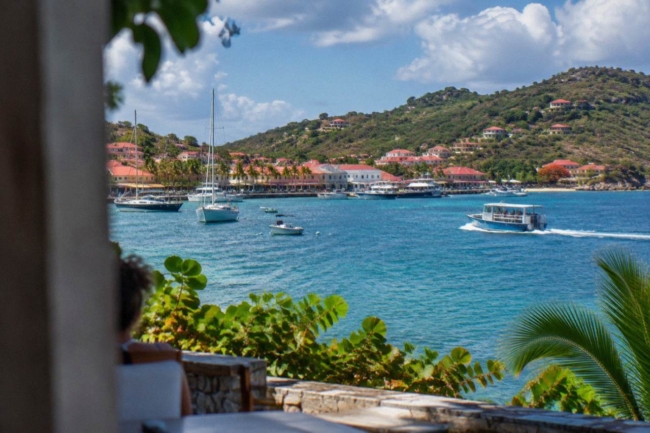 A small ferry boat crossing open blue Caribbean water between green islands under a bright sky