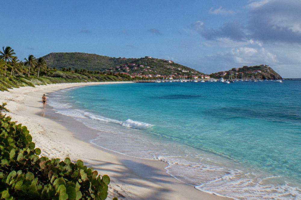 Turquoise water over sandy shallows seen from low hills above a small Caribbean cove