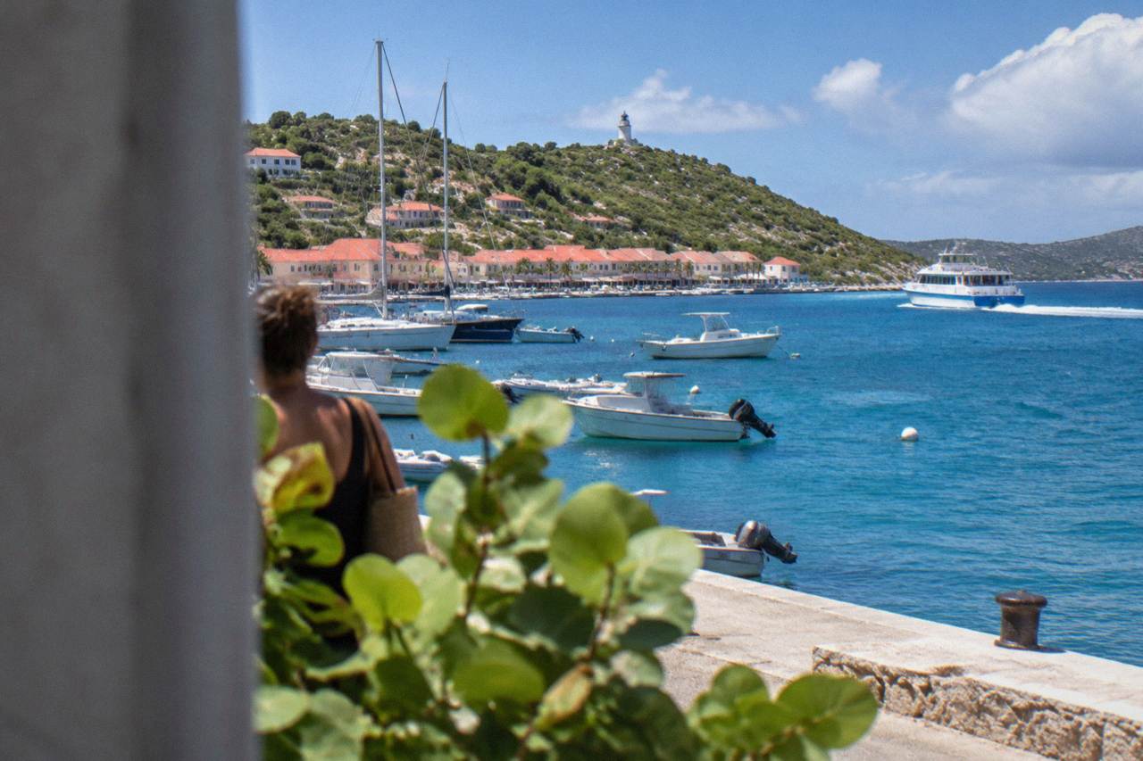 A passenger ferry speeding across open Caribbean water toward a green hilly island