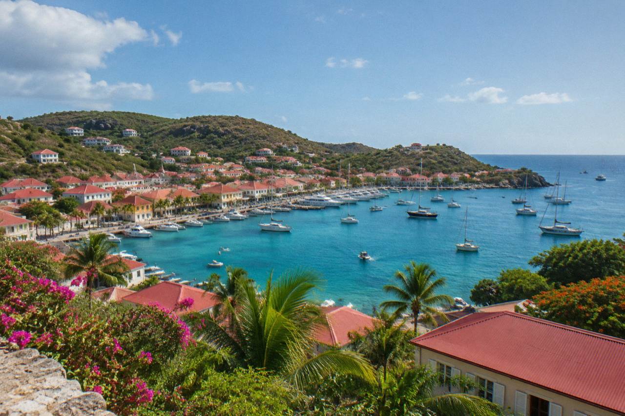 A hillside view over red rooftops and a harbor with turquoise water on a small Caribbean island
