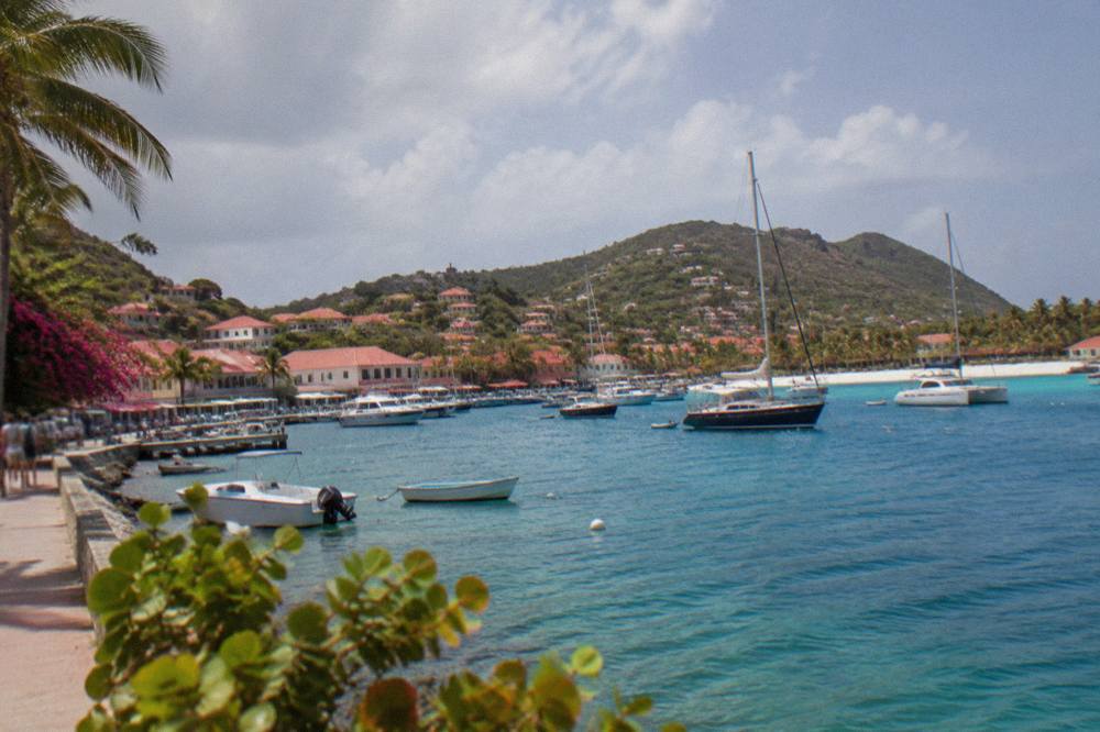 A white sand beach with turquoise water and green hills at the far end of a Caribbean bay