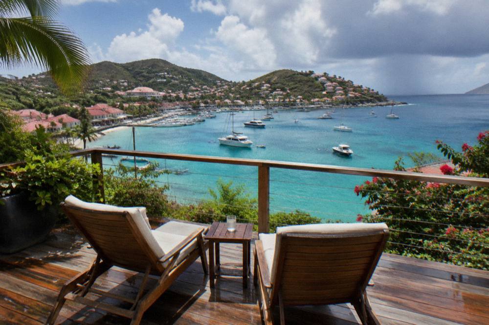 Two deck chairs on a wooden terrace above a turquoise bay in St Barts