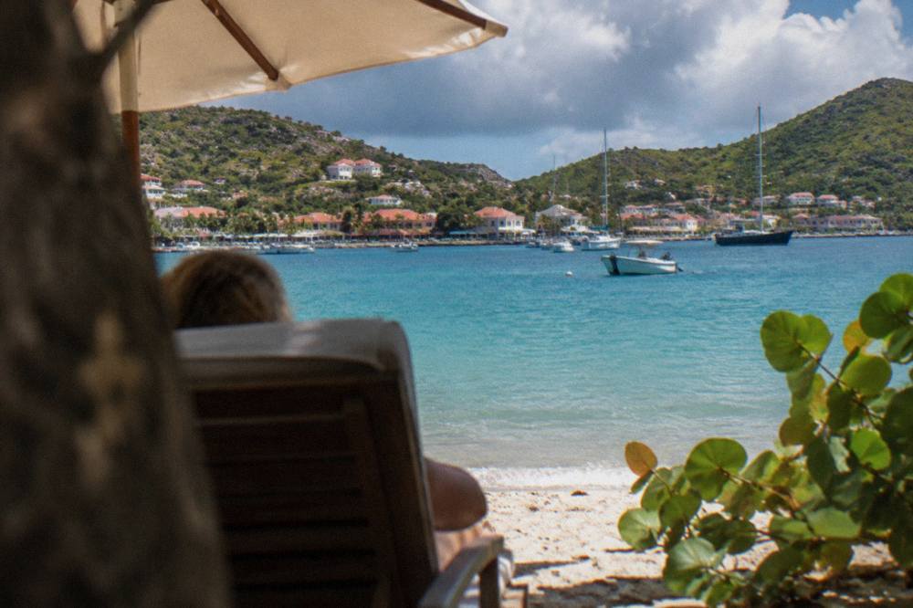 A shaded beach chair looking out over calm turquoise water on a St Barts beach