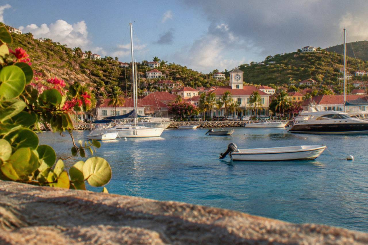 Clock face above the harbor of Gustavia with boats moored in the bay below