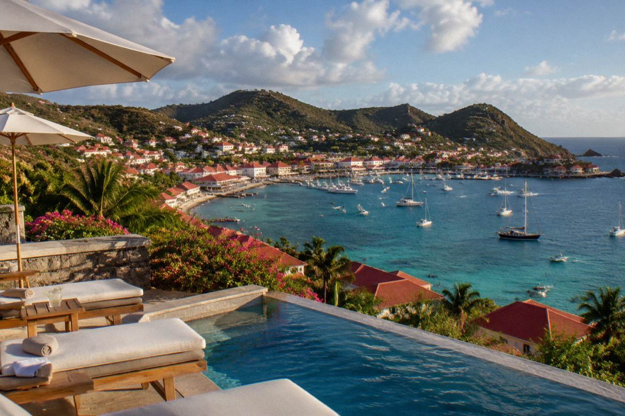 A hillside luxury hotel terrace overlooking a turquoise Caribbean bay on St Barts