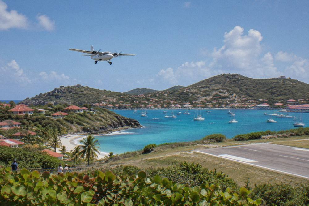 Sailboats anchored in a small Caribbean harbour with hills and low buildings behind