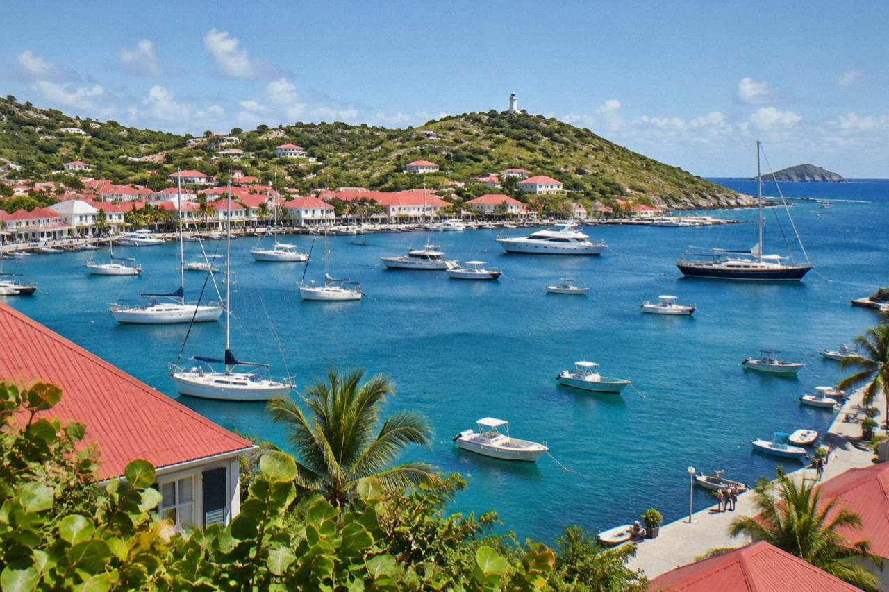Red-roofed buildings of Gustavia harbor under a clear sky with boats at anchor