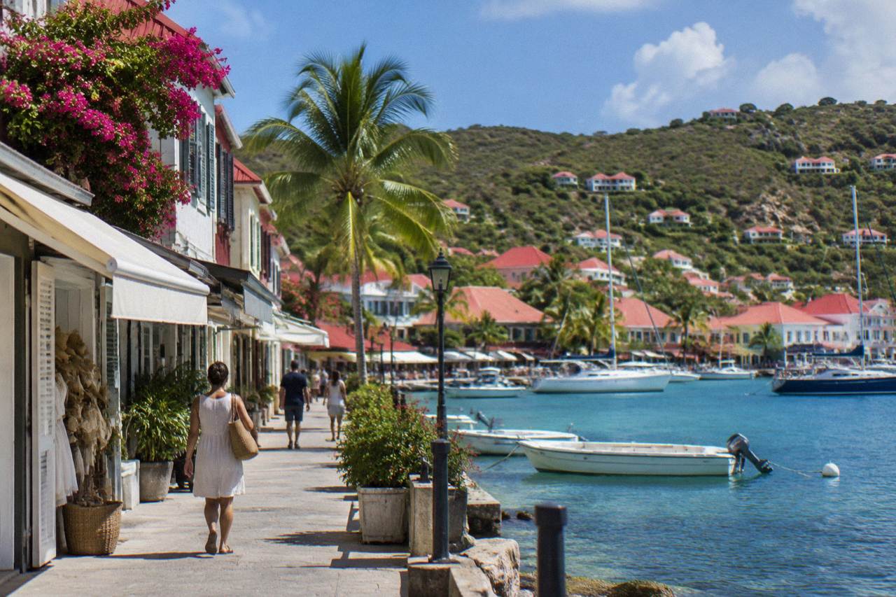 Shopfronts along a harbor street in Gustavia with the Caribbean water behind them