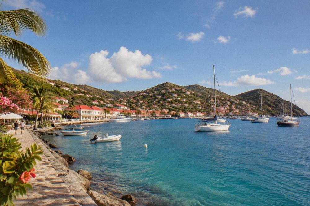 Sailboats moored in clear turquoise water off a green hillside on St Barts