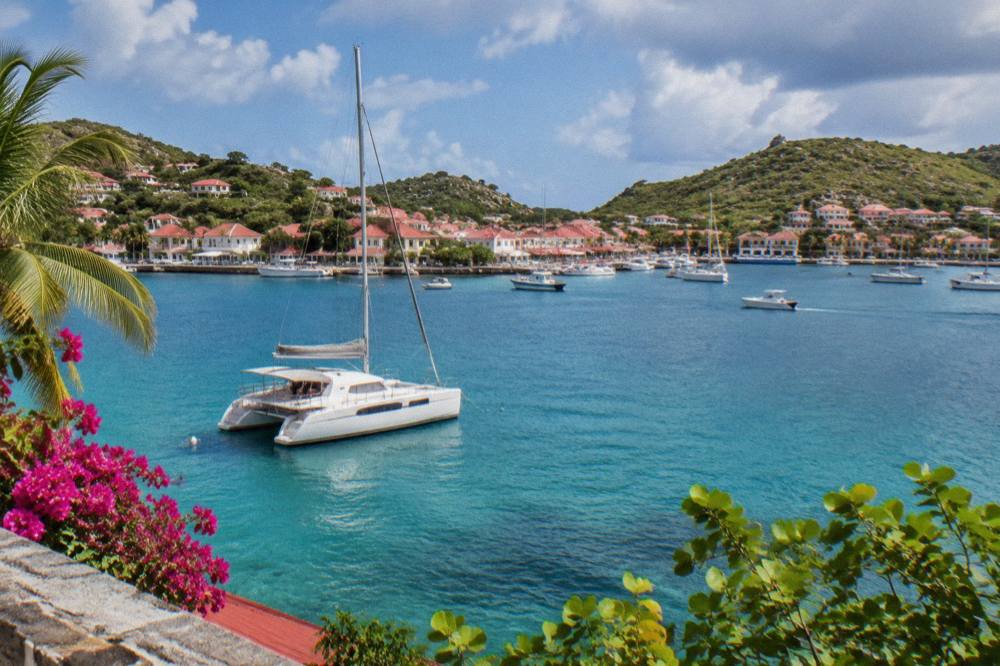 A sailing catamaran moored in a quiet bay on St Barts with hills behind