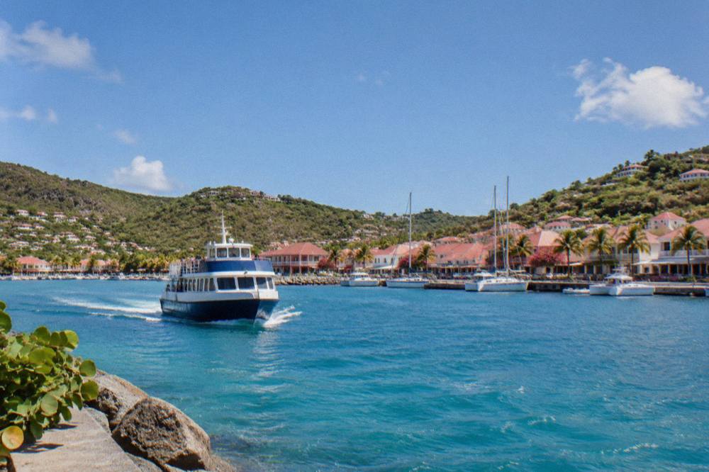 A passenger ferry approaching the harbor front of Gustavia in St Barts under a clear sky