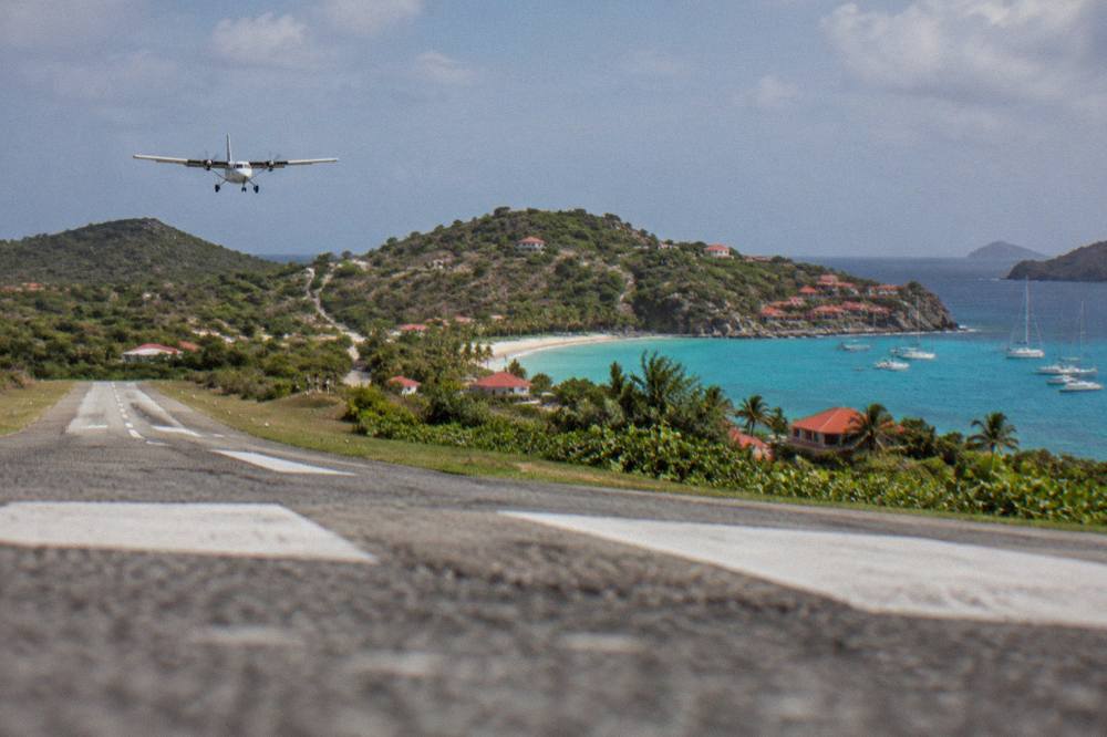 A small turboprop aircraft on a short runway between green hills beside the sea