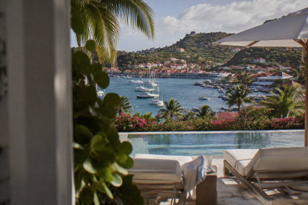 A quiet resort pool terrace with white loungers facing the sea at St Barts