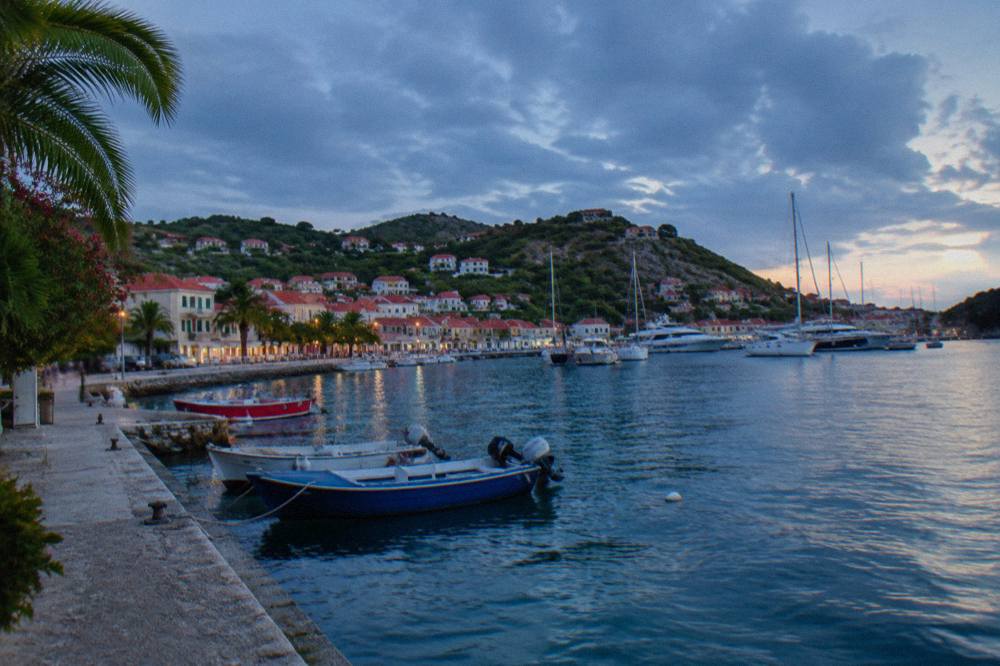 Fishing boats moored in a small Caribbean harbor beside a stone seawall