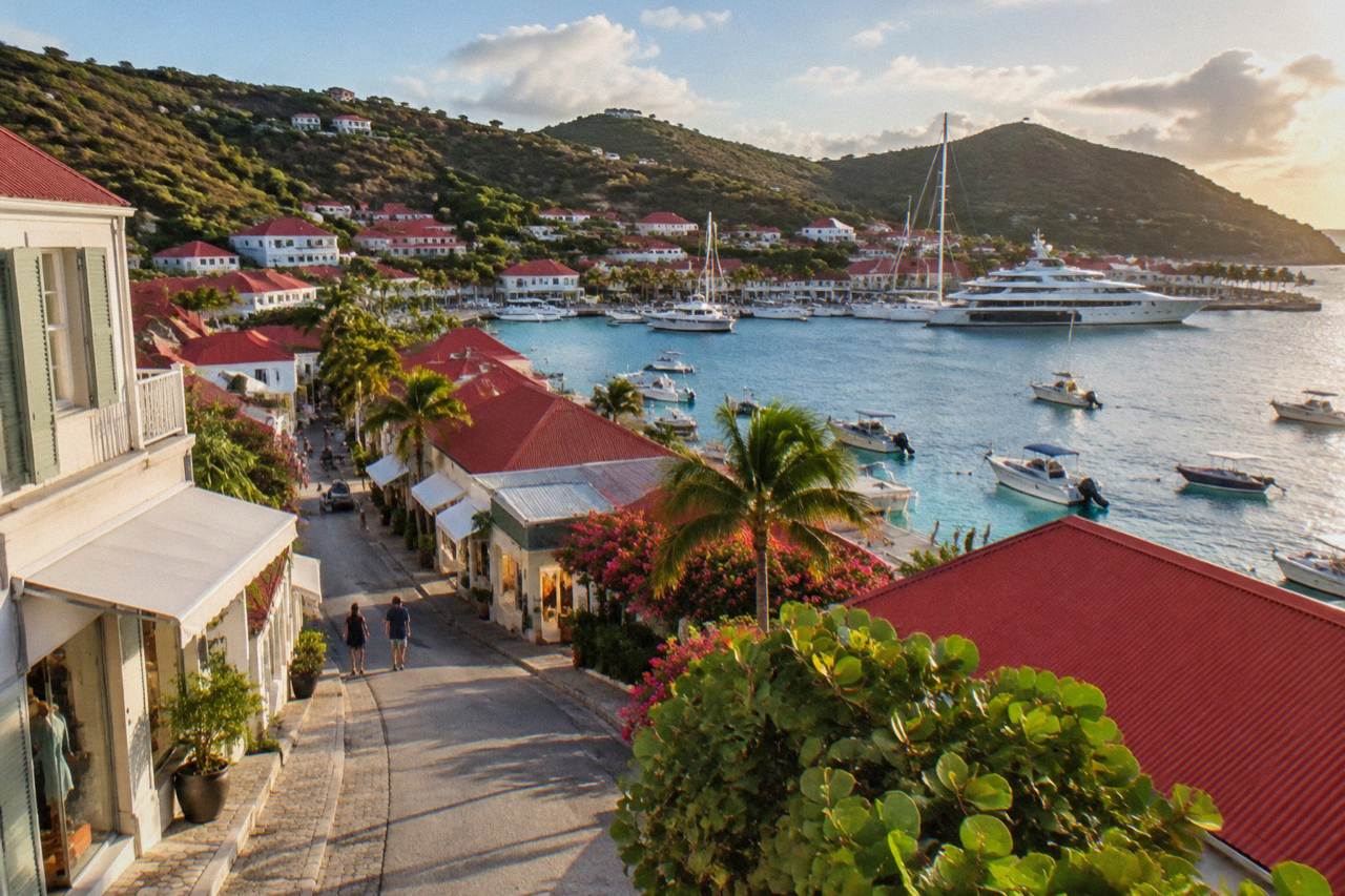 Boutique storefronts along a harbor street in Gustavia with yachts moored in the background