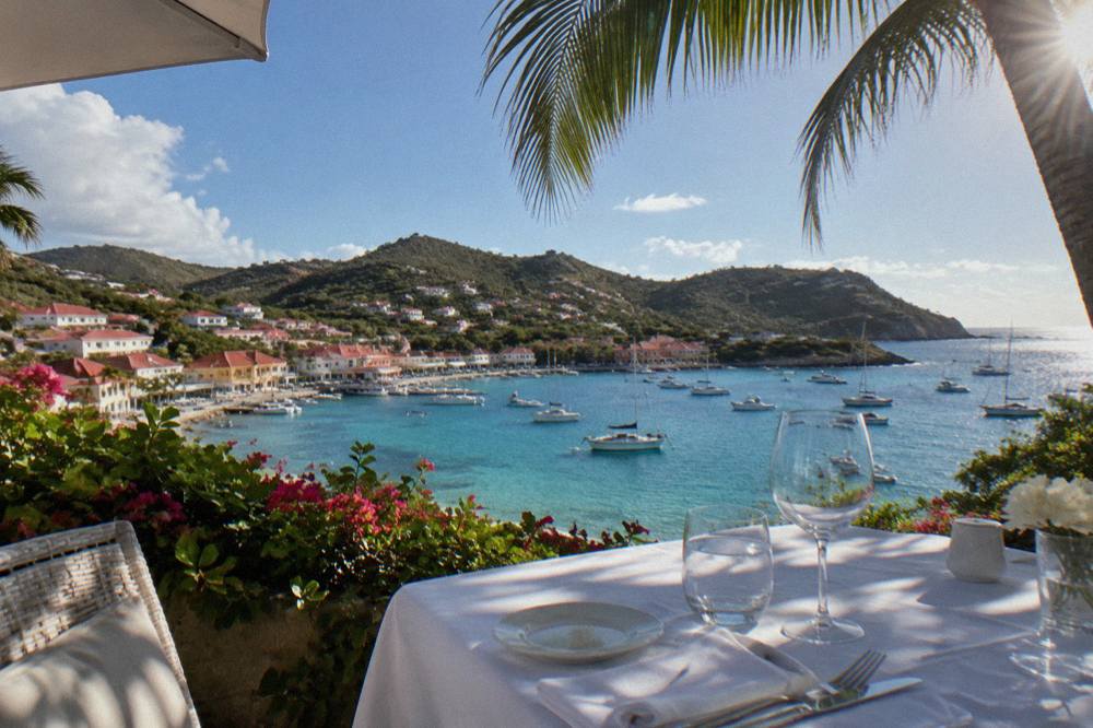 White table setting on an open terrace above a turquoise bay on St Barts