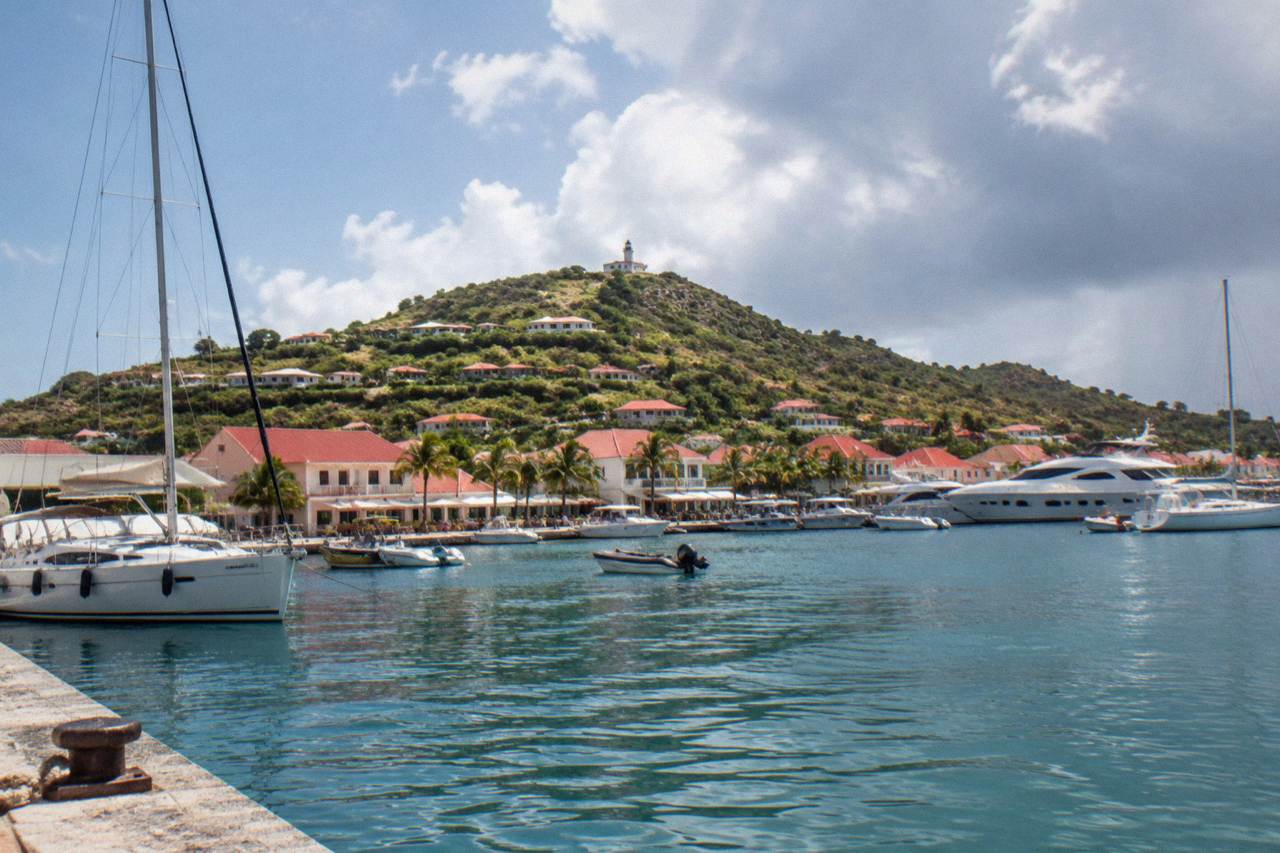 Yachts moored in Gustavia harbor beneath red-roofed buildings on a Caribbean hillside