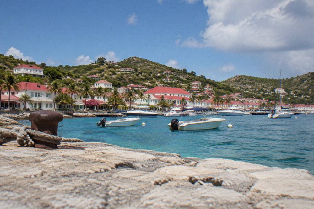 White buildings and red roofs above a small Caribbean harbour with boats