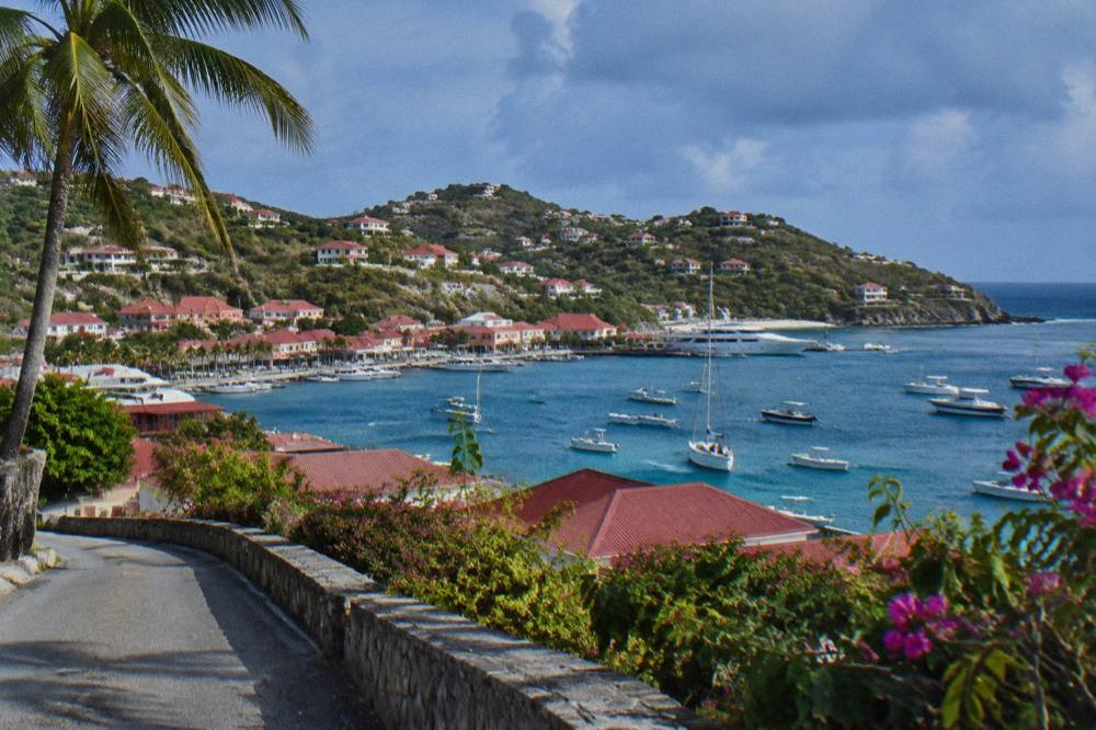 Hillside villas with red roofs above a bay on St Barts seen from a coastal road