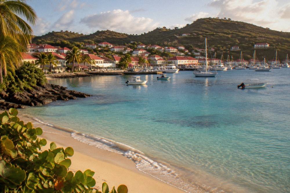 An empty crescent of sand meeting clear shallow water at a bay on St Barts