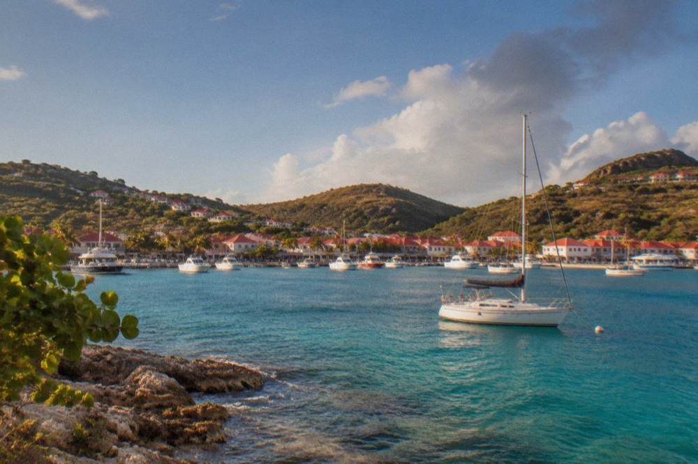 A sailboat anchored in a rocky bay with clear water on St Barts