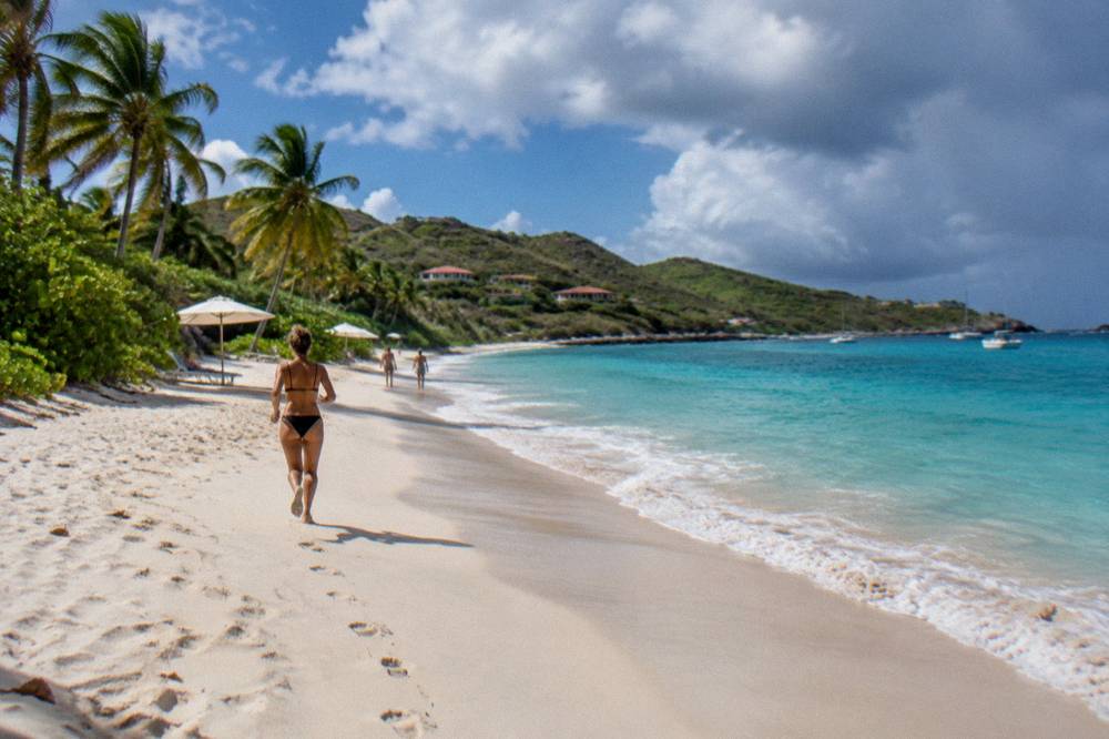 The long crescent of Flamands beach with white sand and a few umbrellas