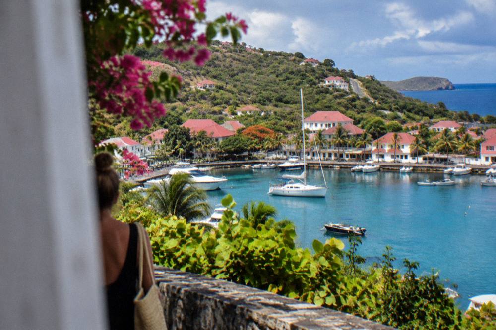 A narrow winding road climbing a green hill on St Barts with sea in the distance