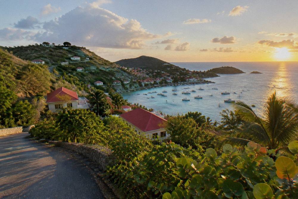 Red-roofed houses on a green hillside overlooking a Caribbean bay