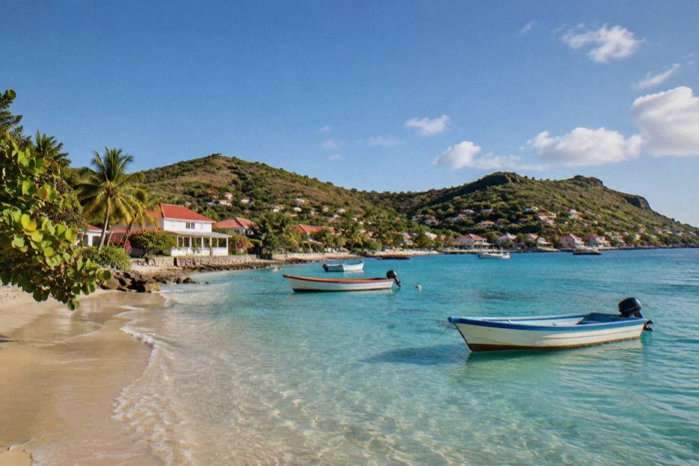 Fishing boats resting in shallow clear water beside a village shoreline at late afternoon