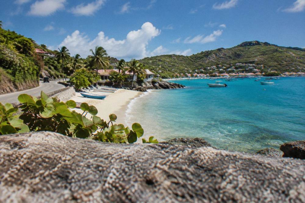 A coastal road curving between green hills and the turquoise Caribbean sea