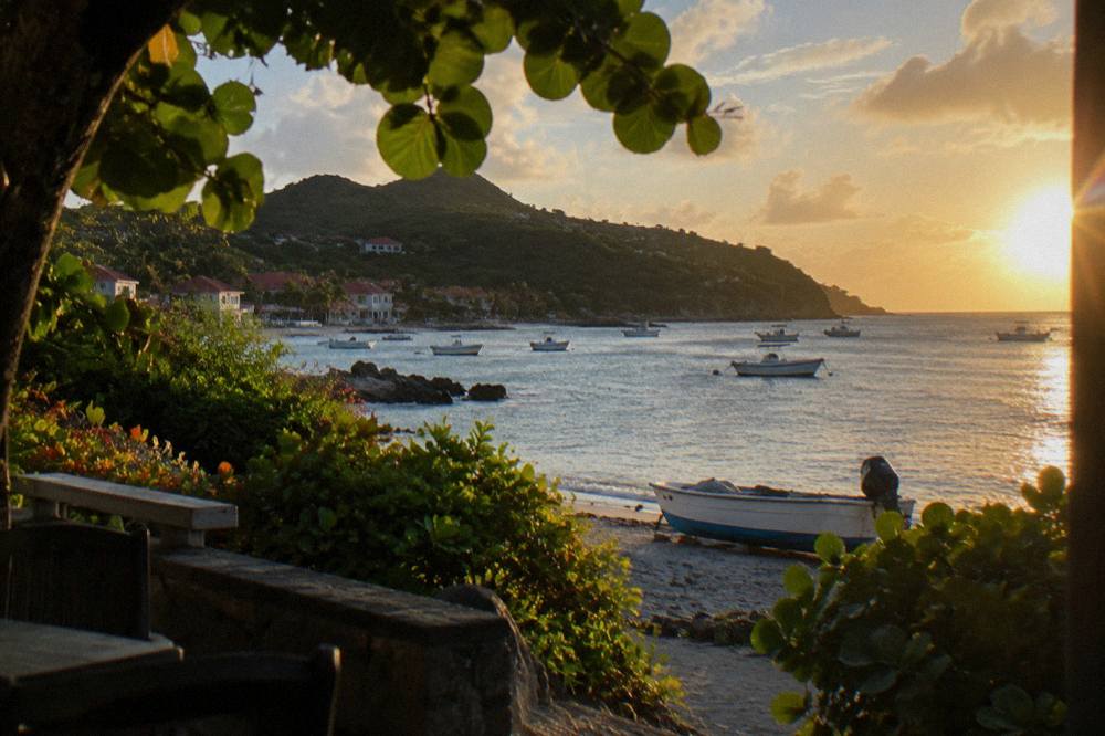 Golden evening light over a calm Caribbean bay with a village silhouette on the shore