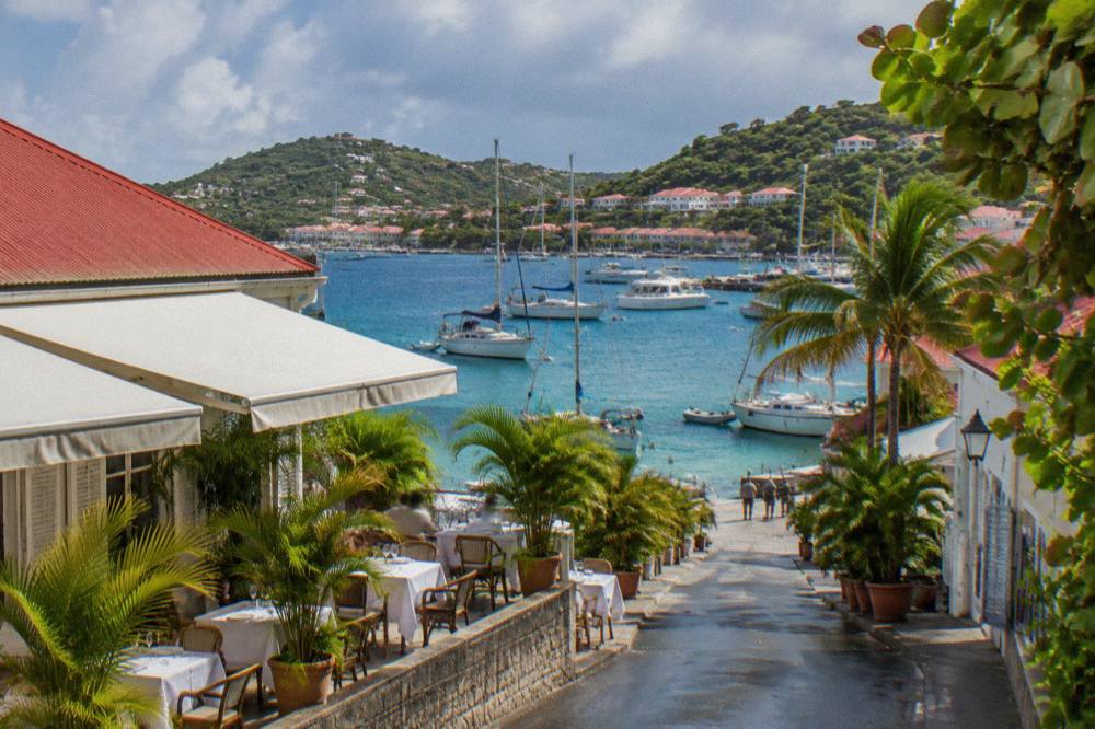 Small restaurant terrace with white tablecloths beside moored sailboats in a Caribbean harbour