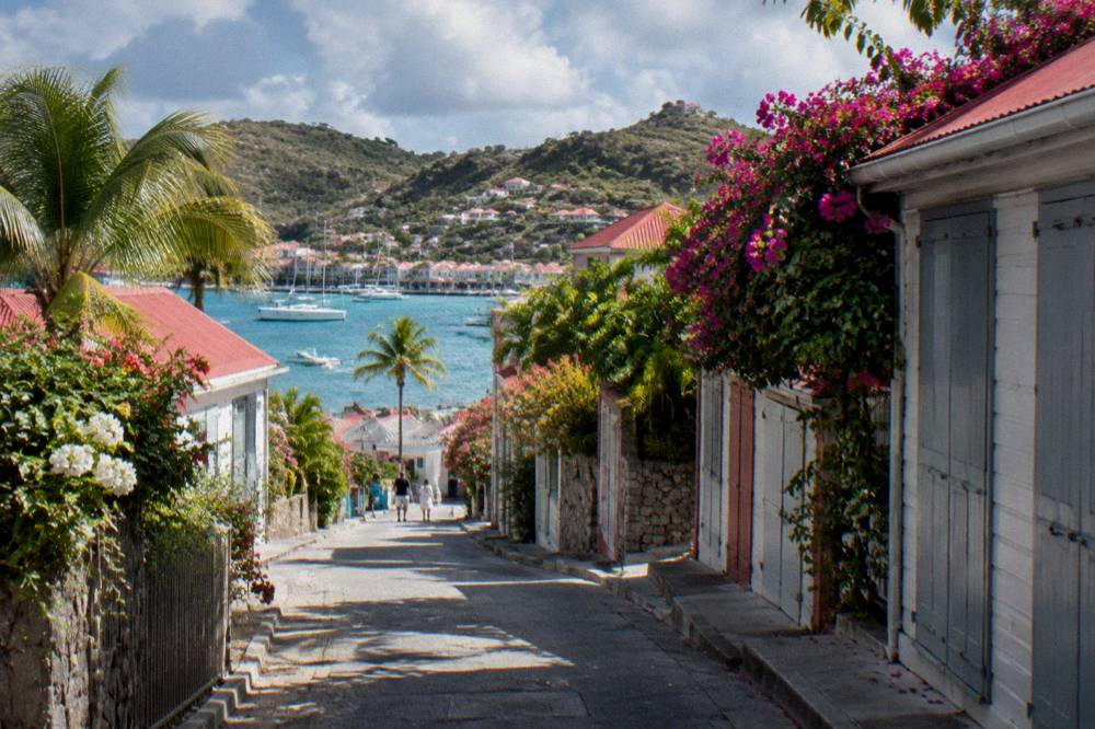 A quiet lane in Gustavia with shuttered shop fronts and blooming tropical plants
