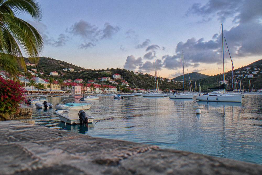 Sailboats anchored in a quiet Caribbean bay with green hills behind