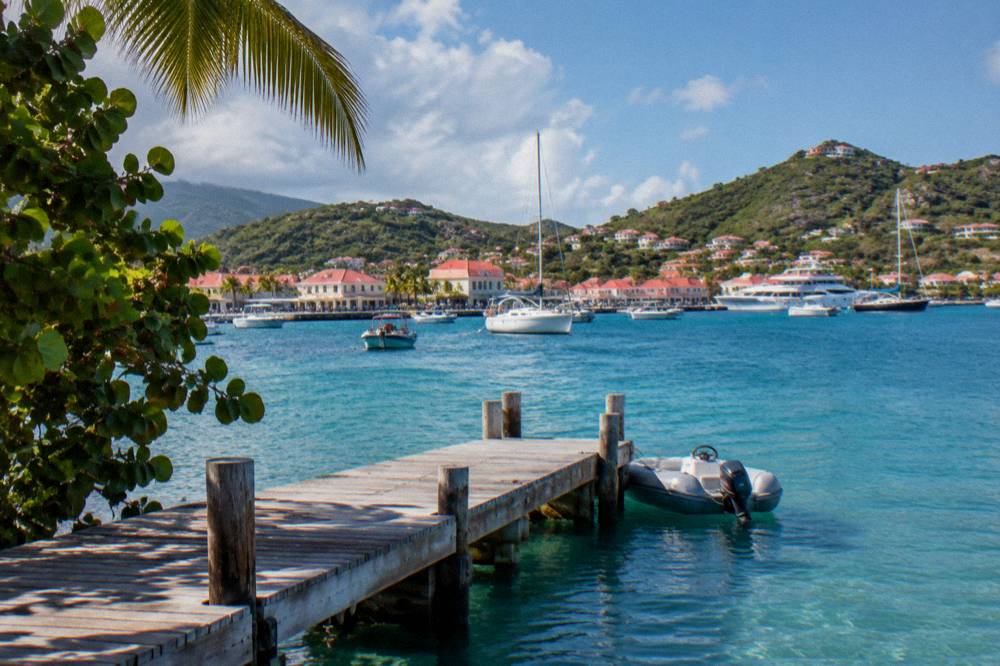 Wooden jetty extending into clear turquoise water with hills in the distance