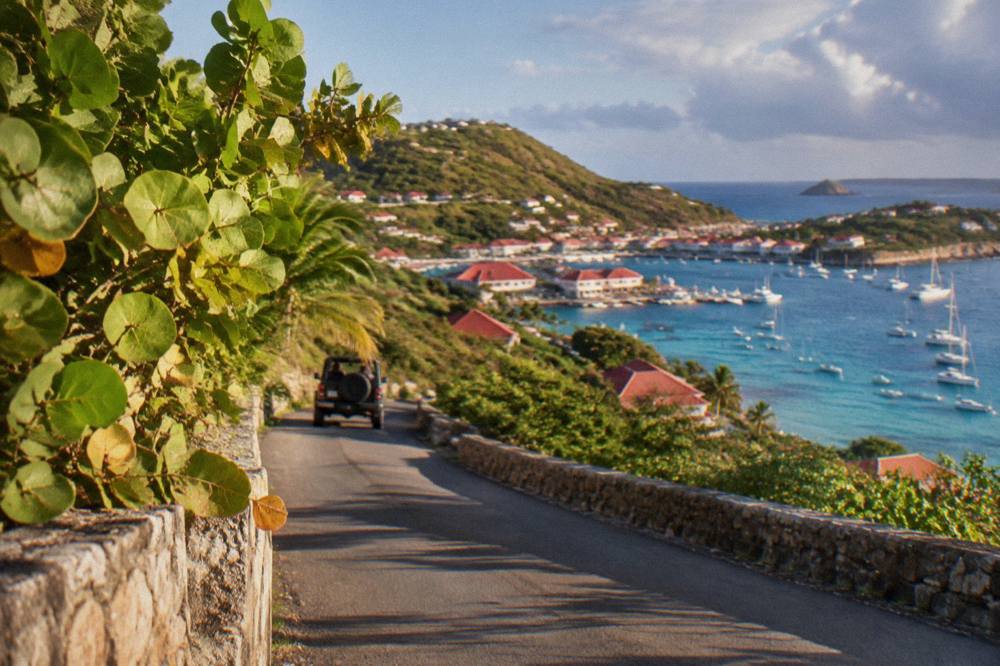 Winding narrow road climbing a green hillside with sea views on a Caribbean island