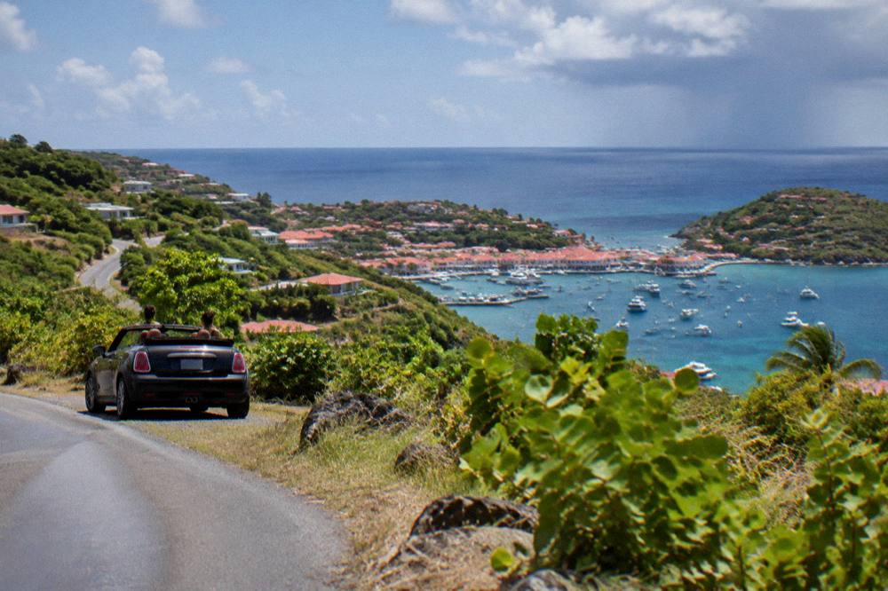 Small open-top car parked beside a narrow road on a green hillside