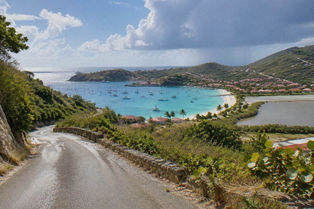 A narrow island road curving between dry green hillsides