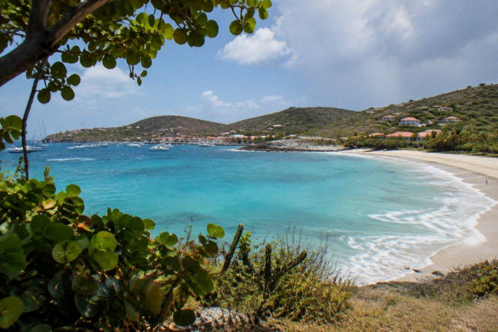 Turquoise water rolling onto a broad empty beach in the Caribbean