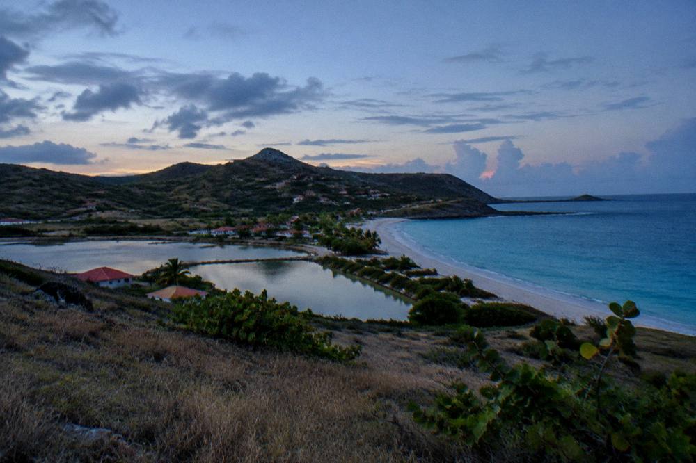 Green hills meeting blue Caribbean sea along a rocky shoreline