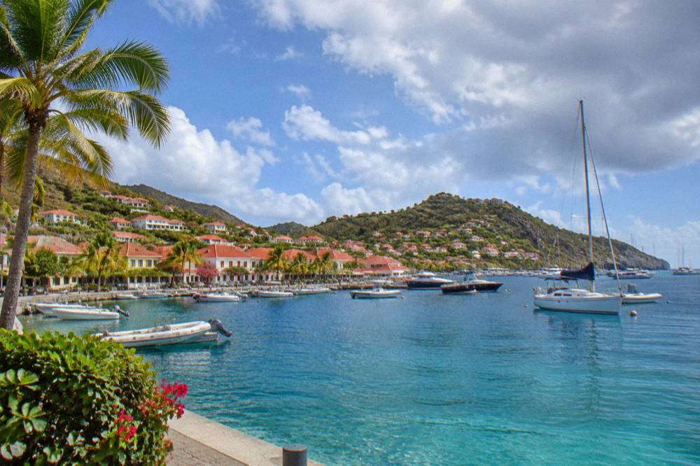 Red-roofed buildings on a hillside above a small Caribbean harbor