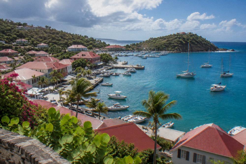 Turquoise bay with a wooded headland and a few anchored sailboats